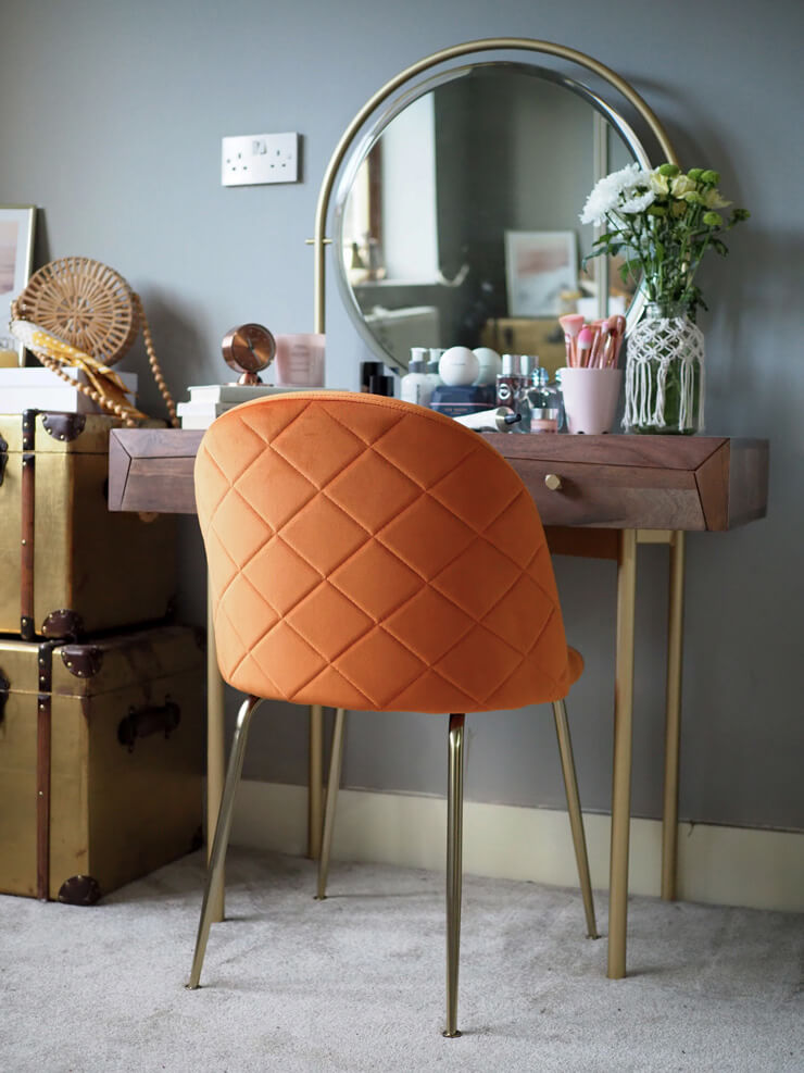 gold and wood vanity with round mirror with velvet orange chair